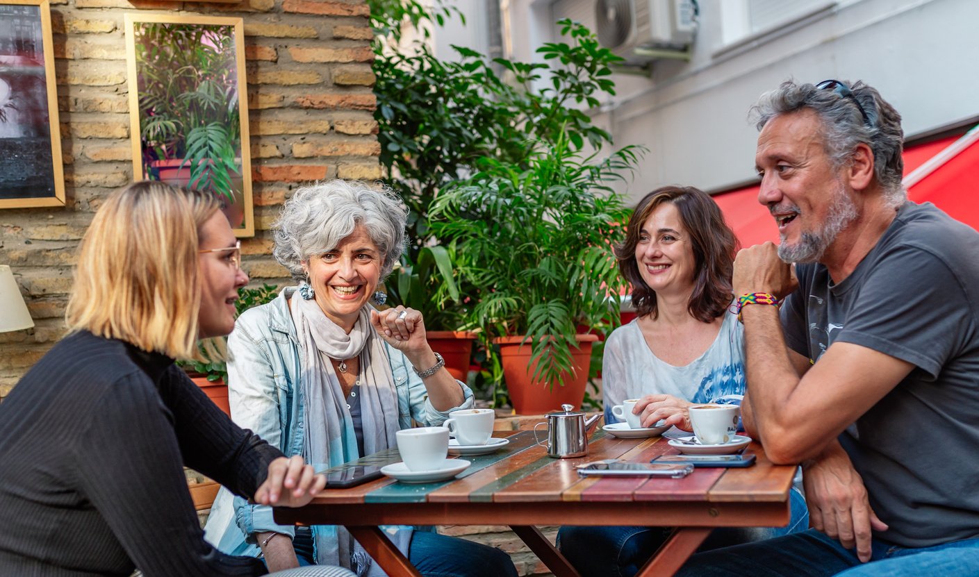 Group of Middle-Aged Friends with Coffee and Gadgets on Table